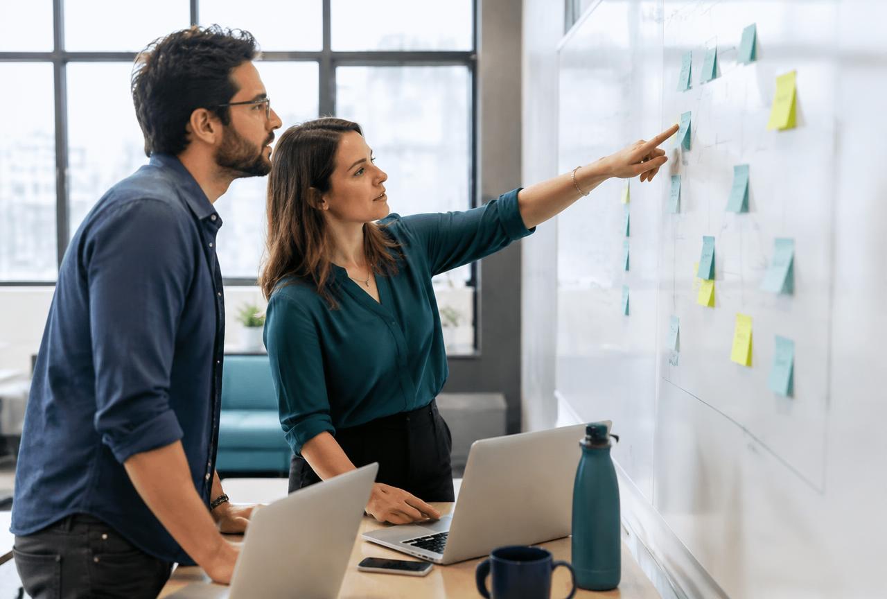 Two colleagues mapping risks and controls on a whiteboard with sticky notes